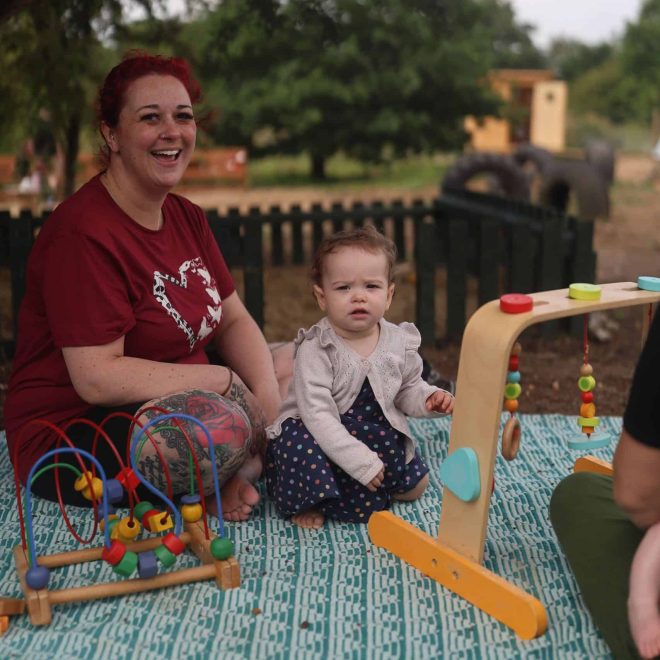 Colorful outdoor play area with children and adult at Playful Paths nature setting.
