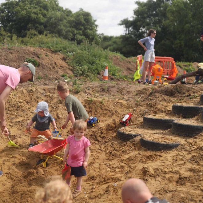 1. Children playing on outdoor nature sand play area with toys and gardening tools.
