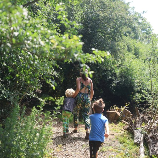 Lush green woodland trail with children and caregiver exploring nature.