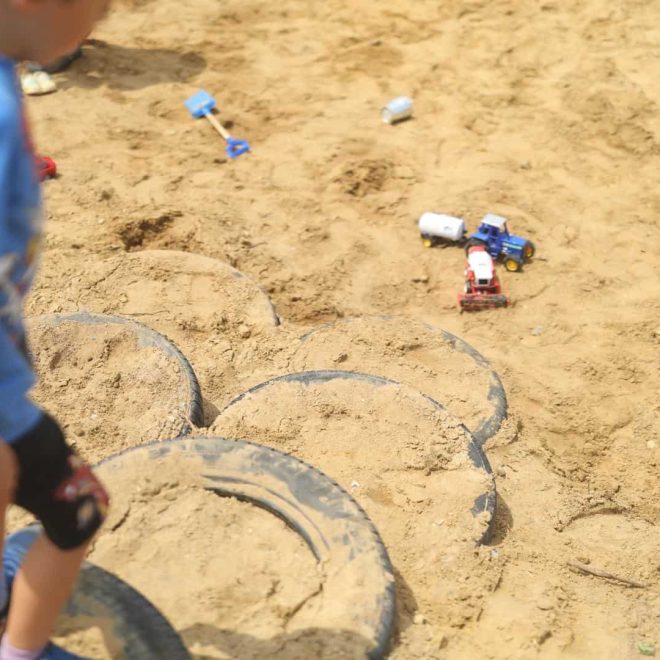 Colorful children's sandbox play area with toy trucks and shovels, ideal for outdoor sensory play.